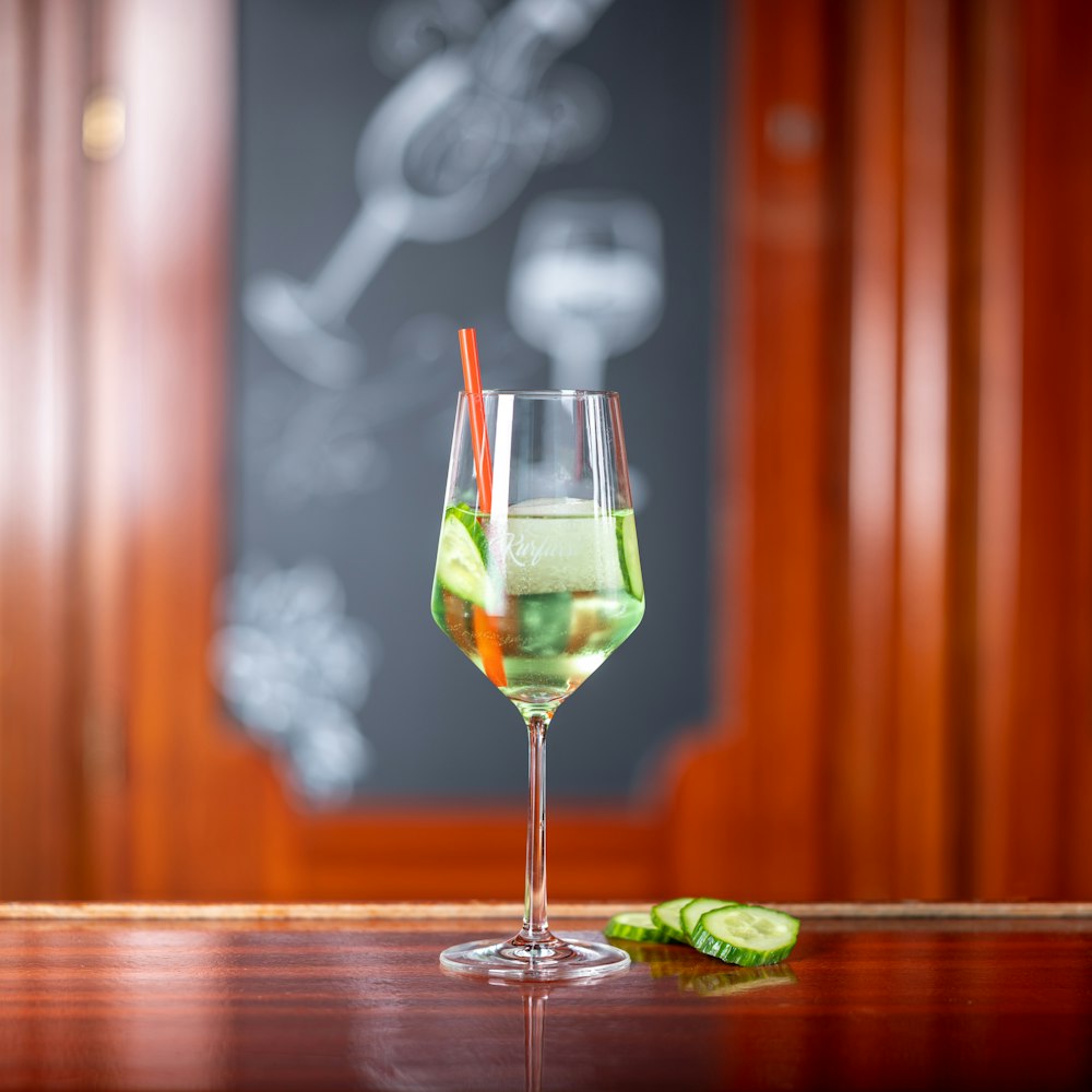 a glass filled with a green liquid and a slice of cucumber