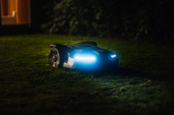 Technician repairing a robotic lawn mower in a clean, modern workshop setting.