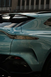 Side view of a luxury vehicle with a shimmering metallic blue paint that catches the sunlight, enhanced by subtle reflections and smooth gradients.