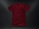 A plain, deep red t-shirt placed against a dark textured background. The garment appears to be crumpled slightly, showing natural folds and shadows. The fabric looks soft, and the shirt is displayed in a casual, relaxed style.