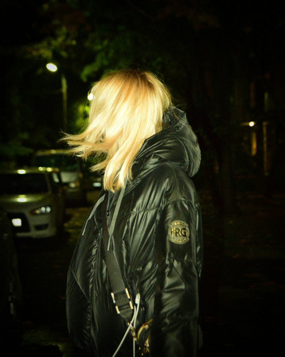 a woman in a black jacket is walking in the dark