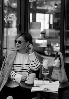 A model enjoying coffee at an outdoor café in stylish attire.