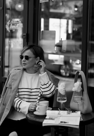 A model enjoying coffee at an outdoor café in stylish attire.