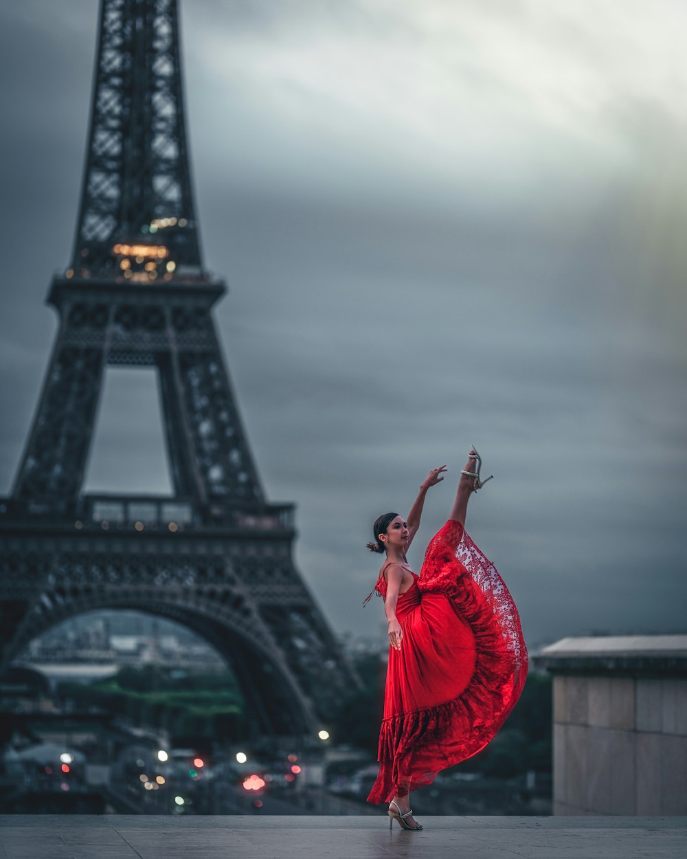 a woman in a red dress dancing in front of the eiffel tower