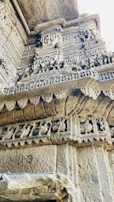 Close-up of weathered carvings on a historic monument wall, telling stories of centuries past.