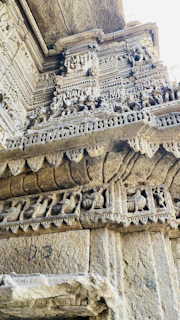 Close-up of weathered carvings on a historic monument wall, telling stories of centuries past.