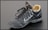 A single black leather sports shoe, featuring a swoosh design on its side. The shoe has black laces loosely tied and a beige inner lining visible at the ankle. It appears slightly worn, with dirt marks on the sole and creases in the leather.