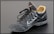 A single black leather sports shoe, featuring a swoosh design on its side. The shoe has black laces loosely tied and a beige inner lining visible at the ankle. It appears slightly worn, with dirt marks on the sole and creases in the leather.