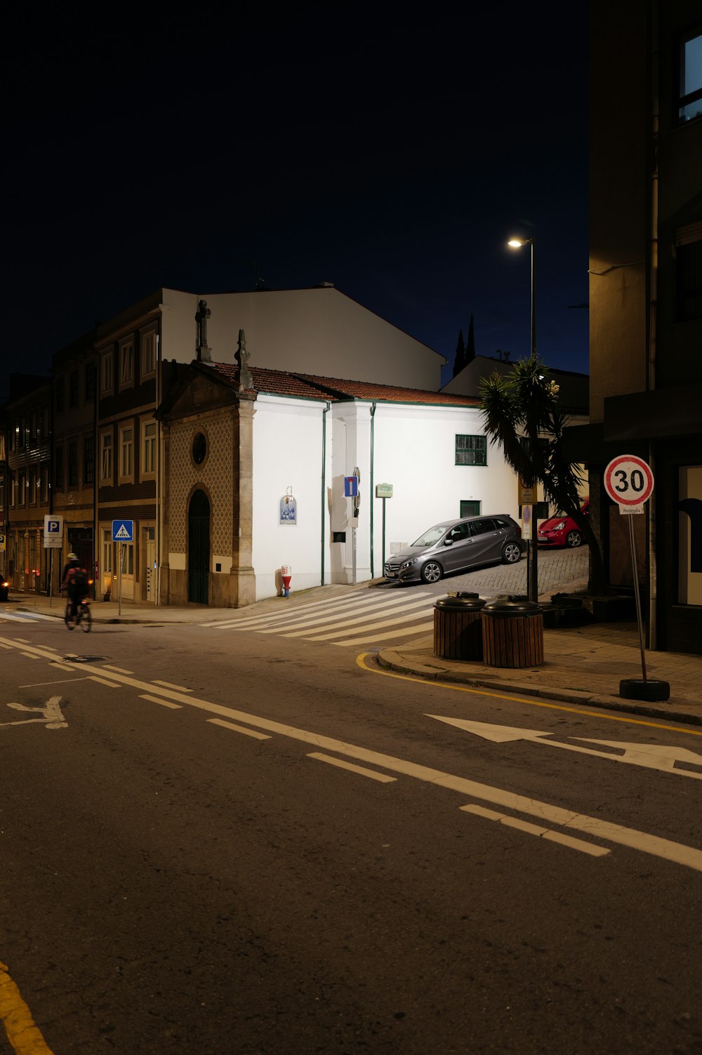 a dark street with a white building on the corner