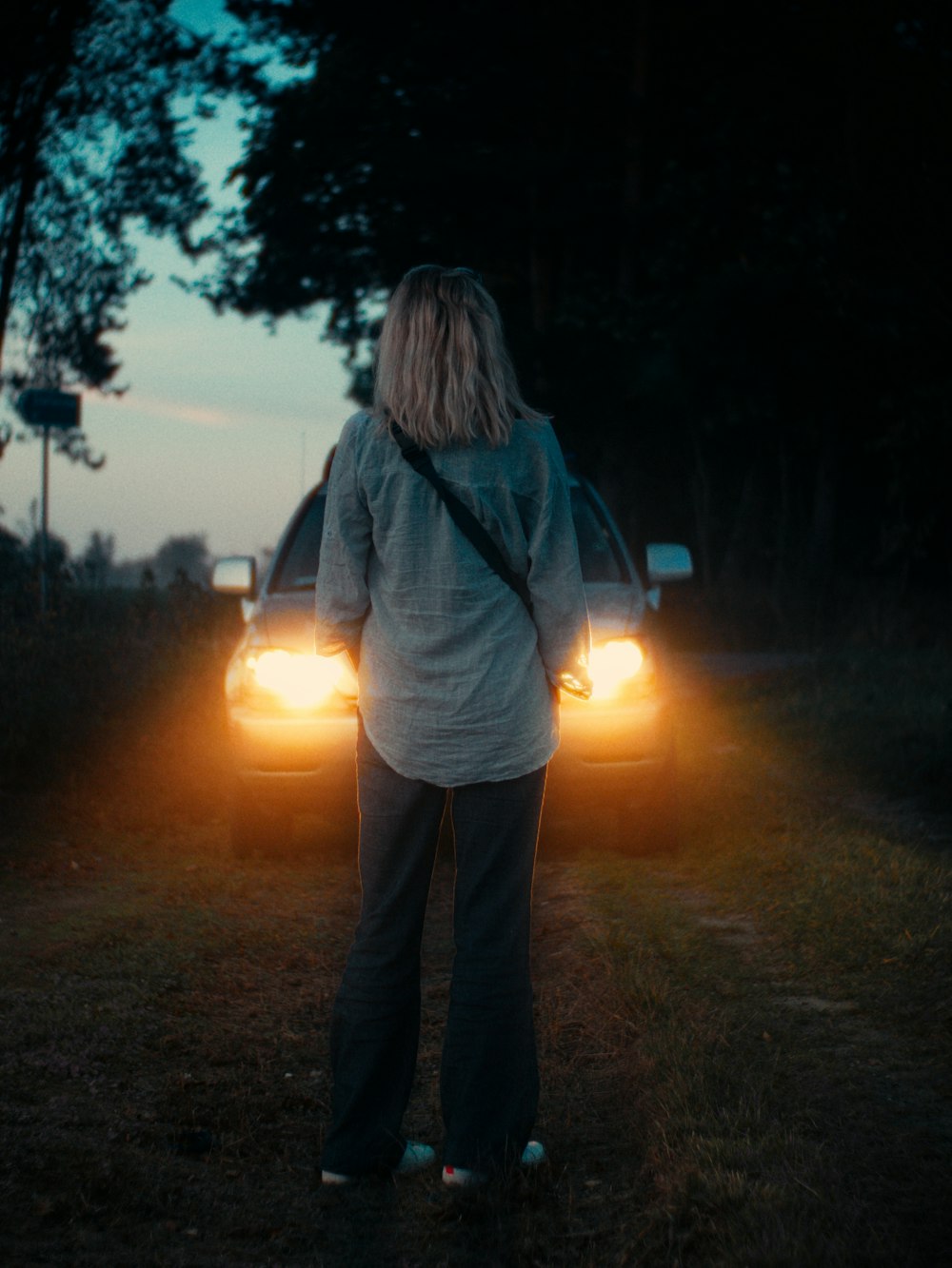 a woman standing in front of a car at night