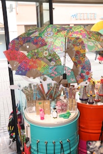 Brightly colored mosquito rackets and sturdy umbrellas shown outside on a sunny day.