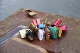 A collection of colorful padlocks is attached to a metal chain on a wet, concrete surface, symbolizing love or commitment.