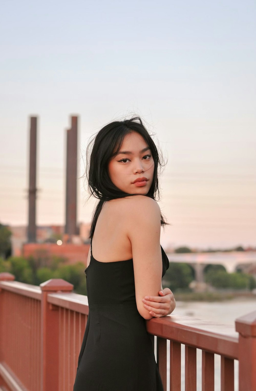 a woman in a black dress standing on a bridge