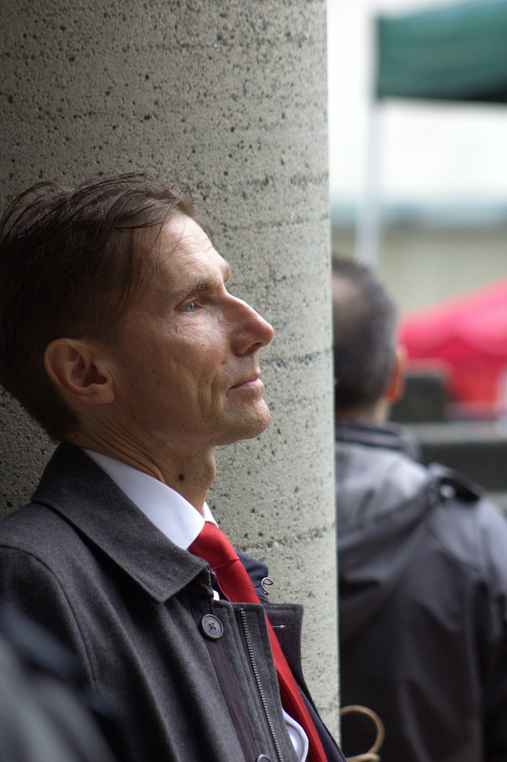 a man in a suit and tie leaning against a pillar