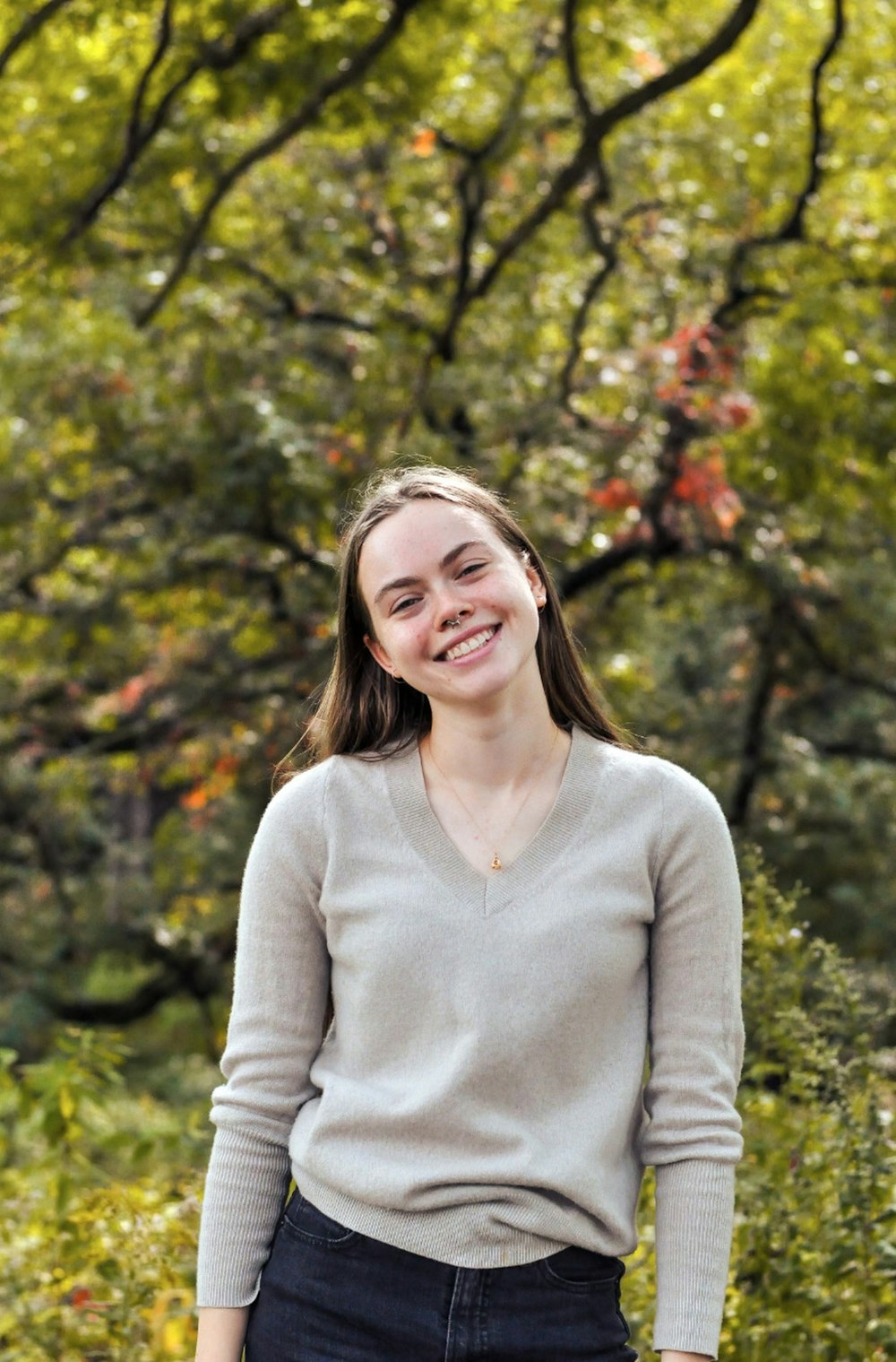 a woman standing in front of a tree smiling