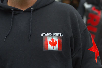 A cozy red hoodie featuring a modern maple leaf design on the chest