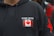 A black hoodie features a patch with the Canadian flag and the words 'Stand United' on the chest. The hoodie includes drawstrings and a red star design on the sleeve.