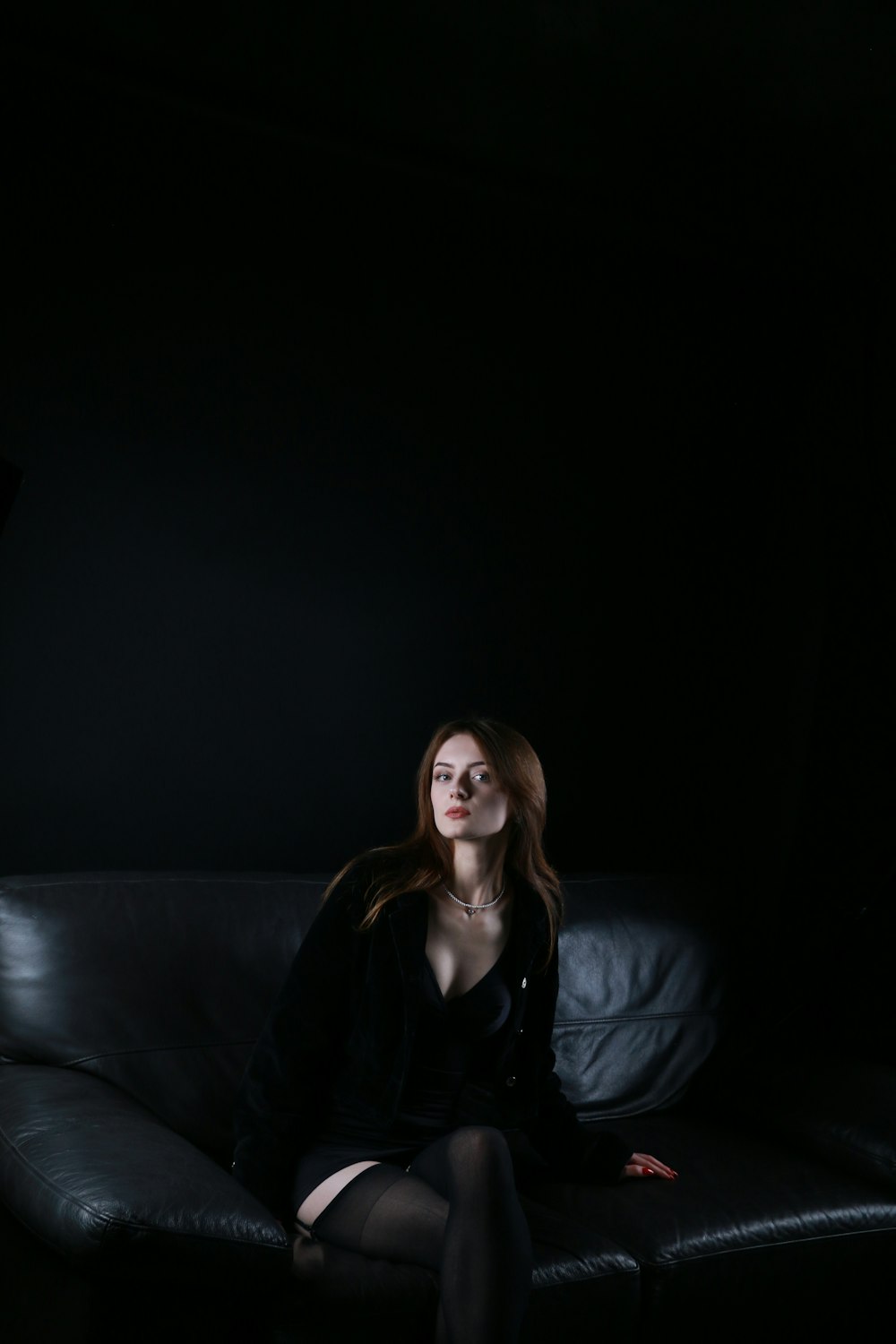 a woman sitting on top of a black couch