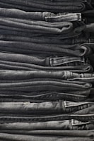 A neatly arranged collection of classic denim jeans and shirts on a minimalist shelf