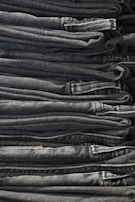 Overhead shot of folded denim jeans stacked neatly beside rolled-up cuffed sleeves.