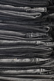 A neatly folded stack of premium denim jeans showcasing different washes and textures.