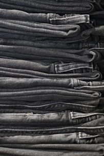 Close-up of a stack of classic denim jeans with varied washes, neatly folded on a minimalistic shelf