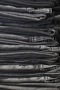 A neatly arranged collection of classic denim jeans and shirts on a minimalist shelf