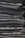 A neatly arranged stack of folded dark gray and black denim jeans, showing clean lines and uniformity.