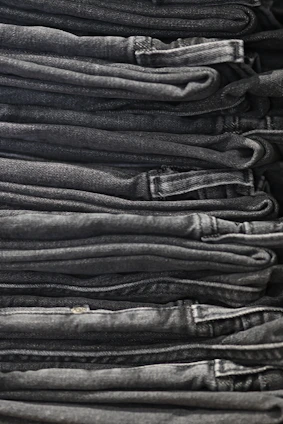 A neatly folded stack of denim jeans in various washes and styles.