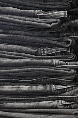 A neatly folded stack of men's shirts and jeans showcasing quality fabric and craftsmanship.