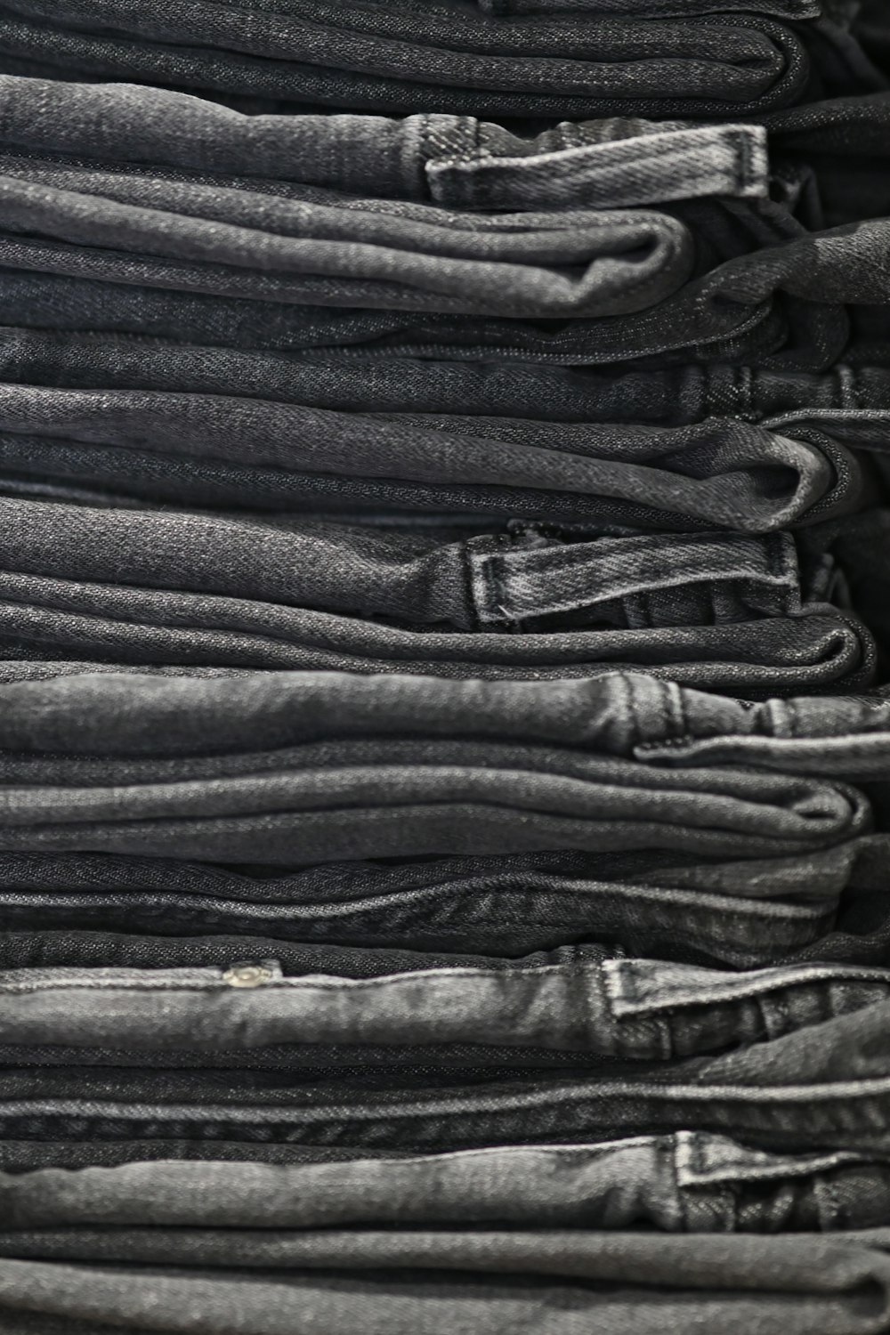 a pile of black jeans stacked on top of each other