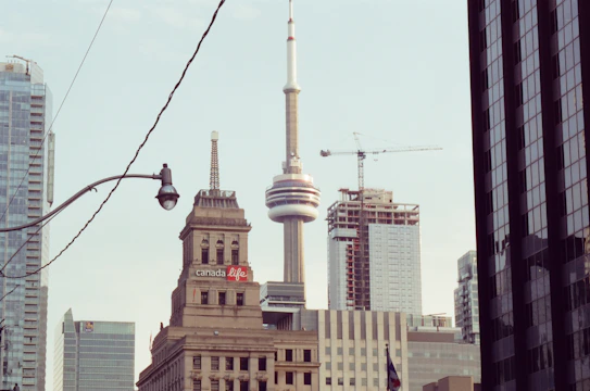 Sunlit skyline of Toronto with new construction cranes in the foreground.