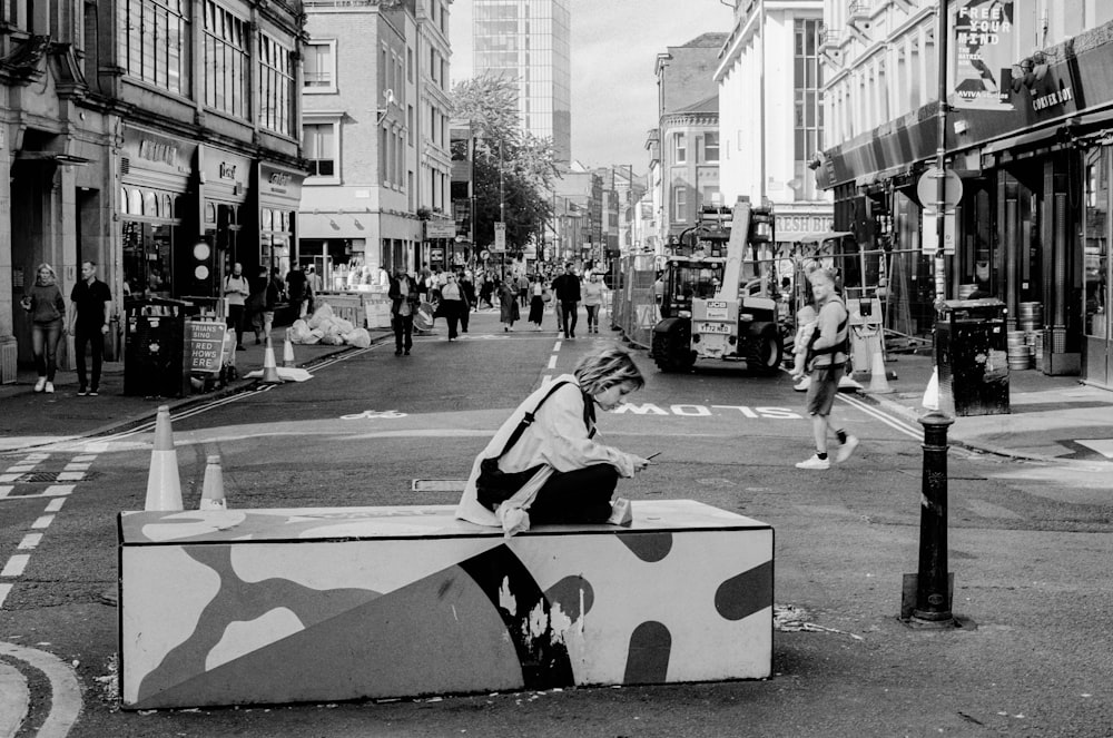 a woman sitting on a box in the middle of a street