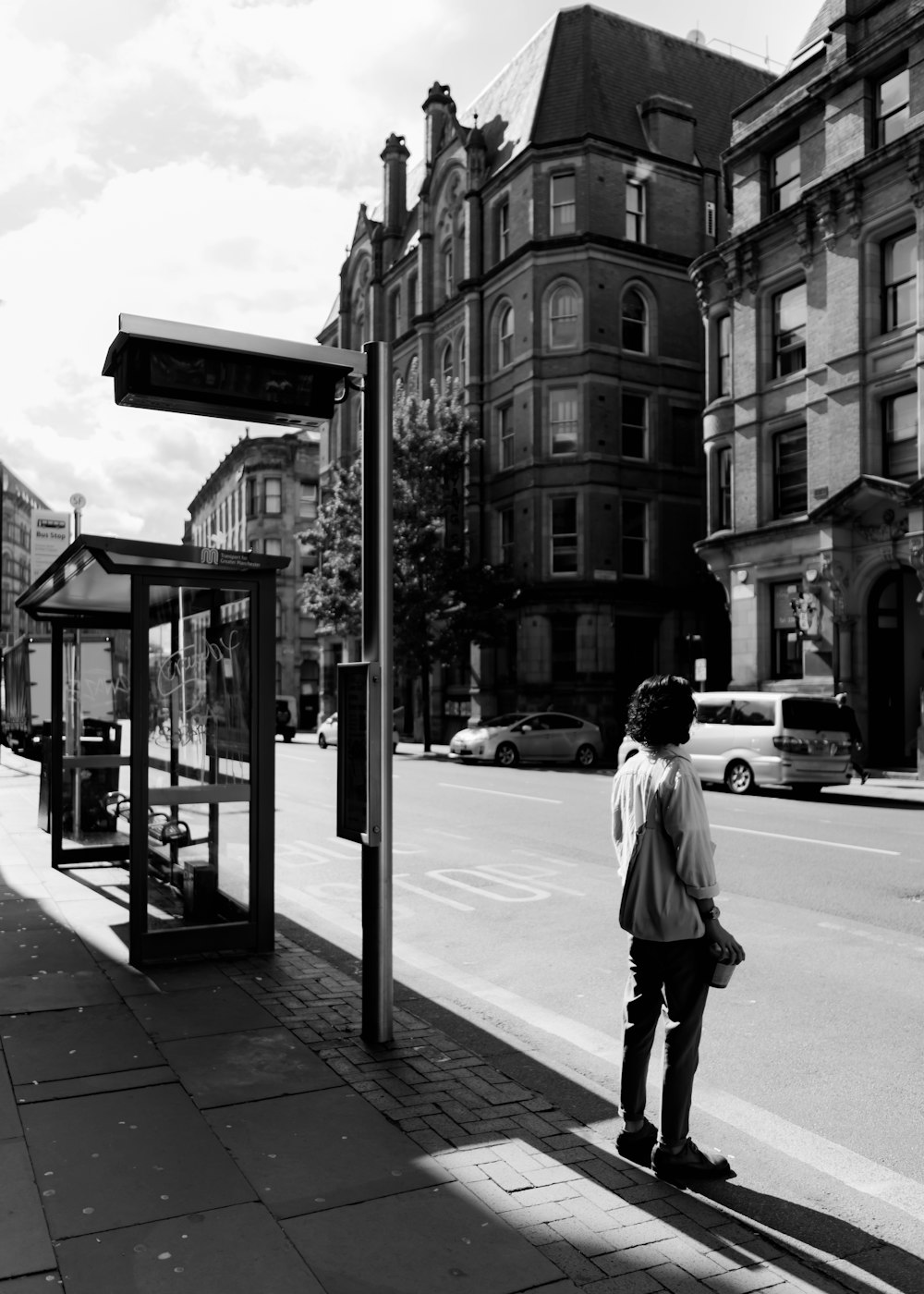 a person standing on a sidewalk next to a bus stop