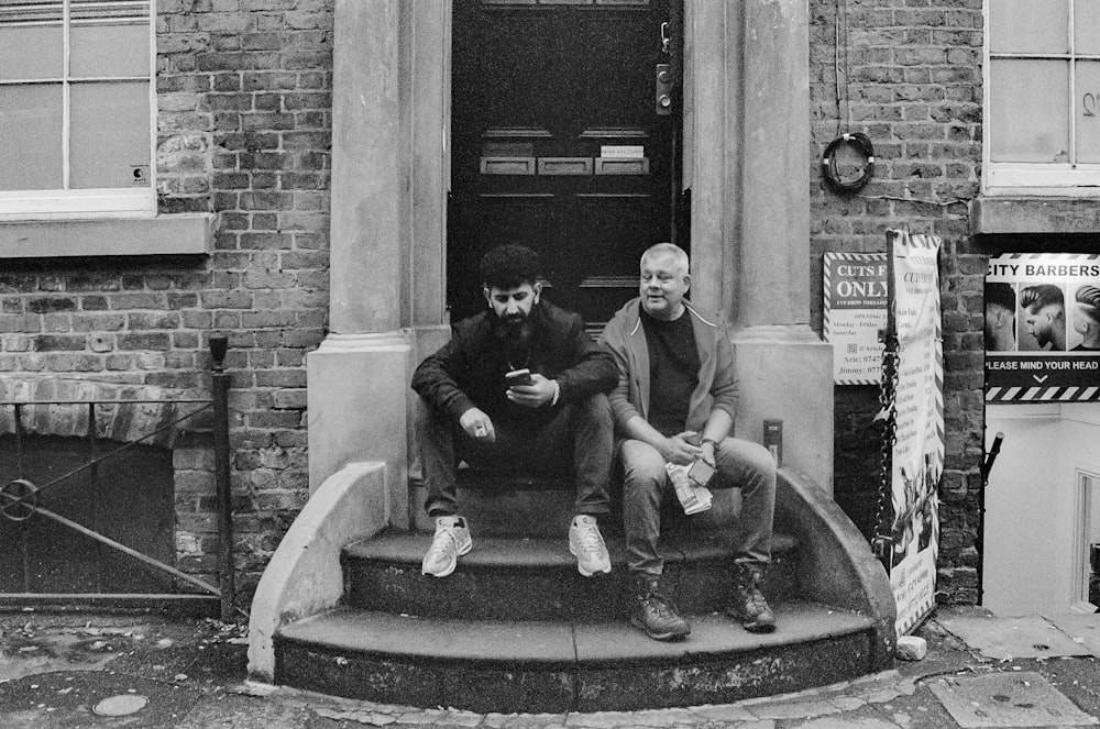 two men sitting on the steps of a building