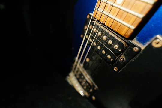 Close-up of a deep blue guitar resting on a noir-themed velvet cloth.