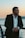 a man in a suit standing next to the ocean