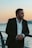 a man in a suit standing next to the ocean