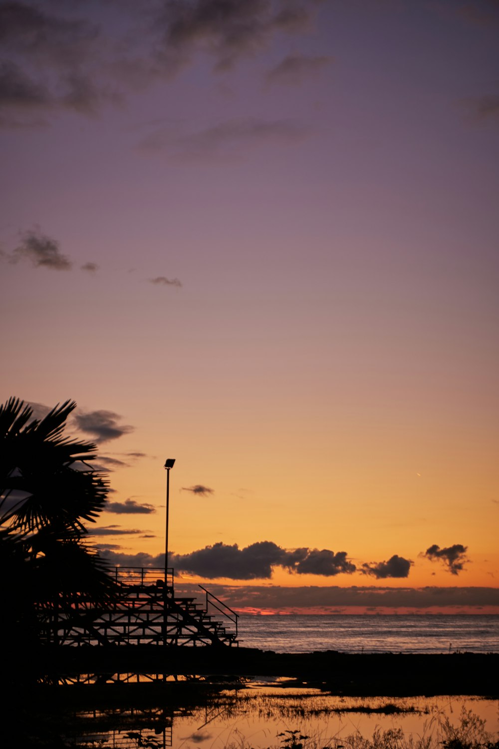 a sunset view of the ocean with a pier in the foreground