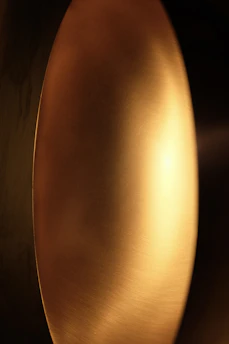 Abstract close-up of brushed gold texture reflecting soft light, evoking warmth and refinement.