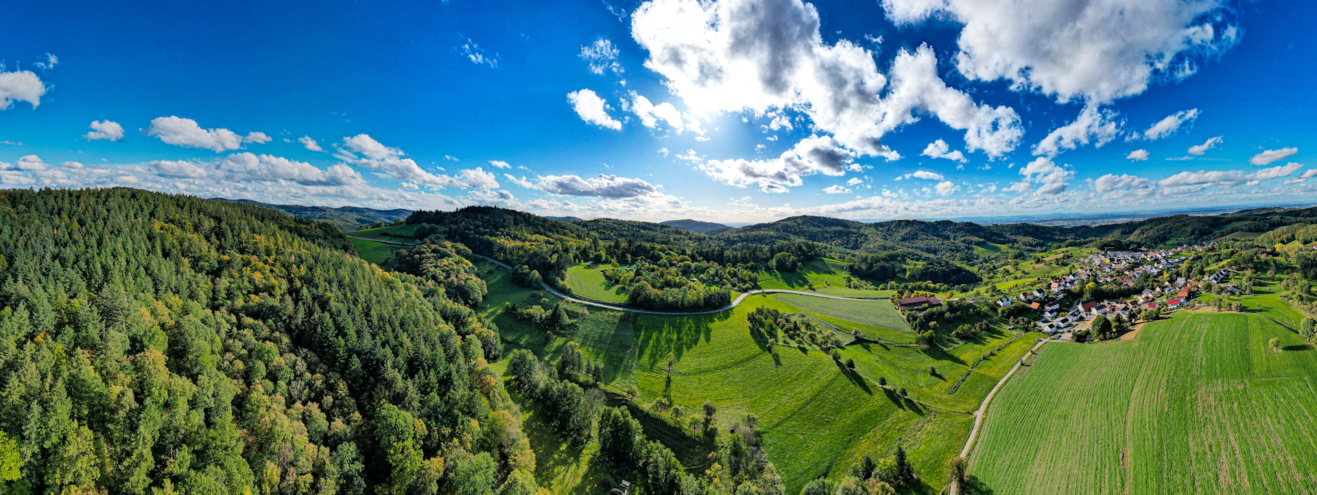 A panoramic shot capturing the serene landscape of Letibunga village with rolling hills and lush greenery.