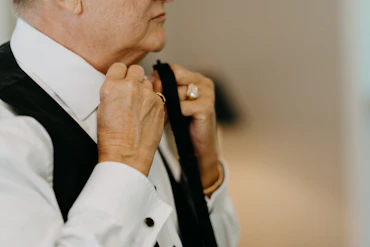 an older woman adjusting her tie in a room