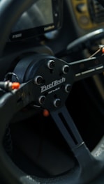Close-up of a sim racing setup featuring branded pedals and steering wheel with influencer branding.
