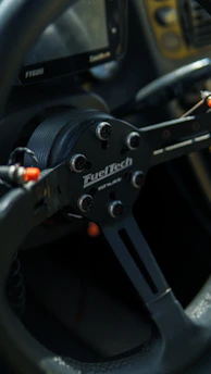 A close-up shot of a sim racing wheel and pedals setup with a vibrant race track displayed on the screen in the background.