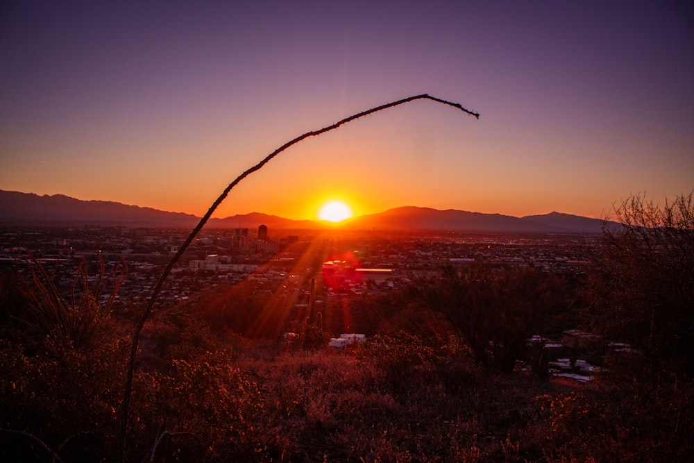 the sun is setting over a city in the distance