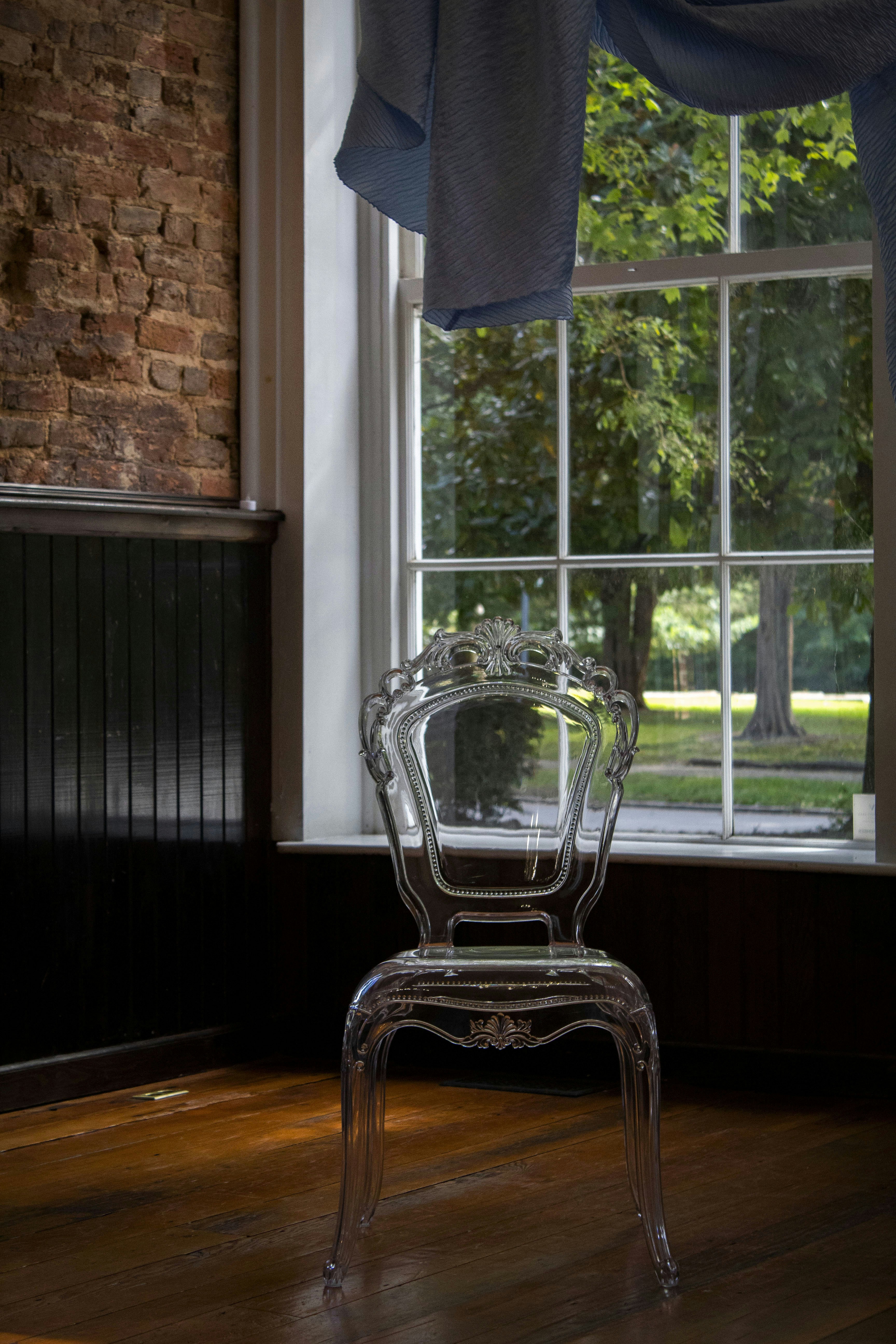 une chaise transparente assise devant une fenêtre