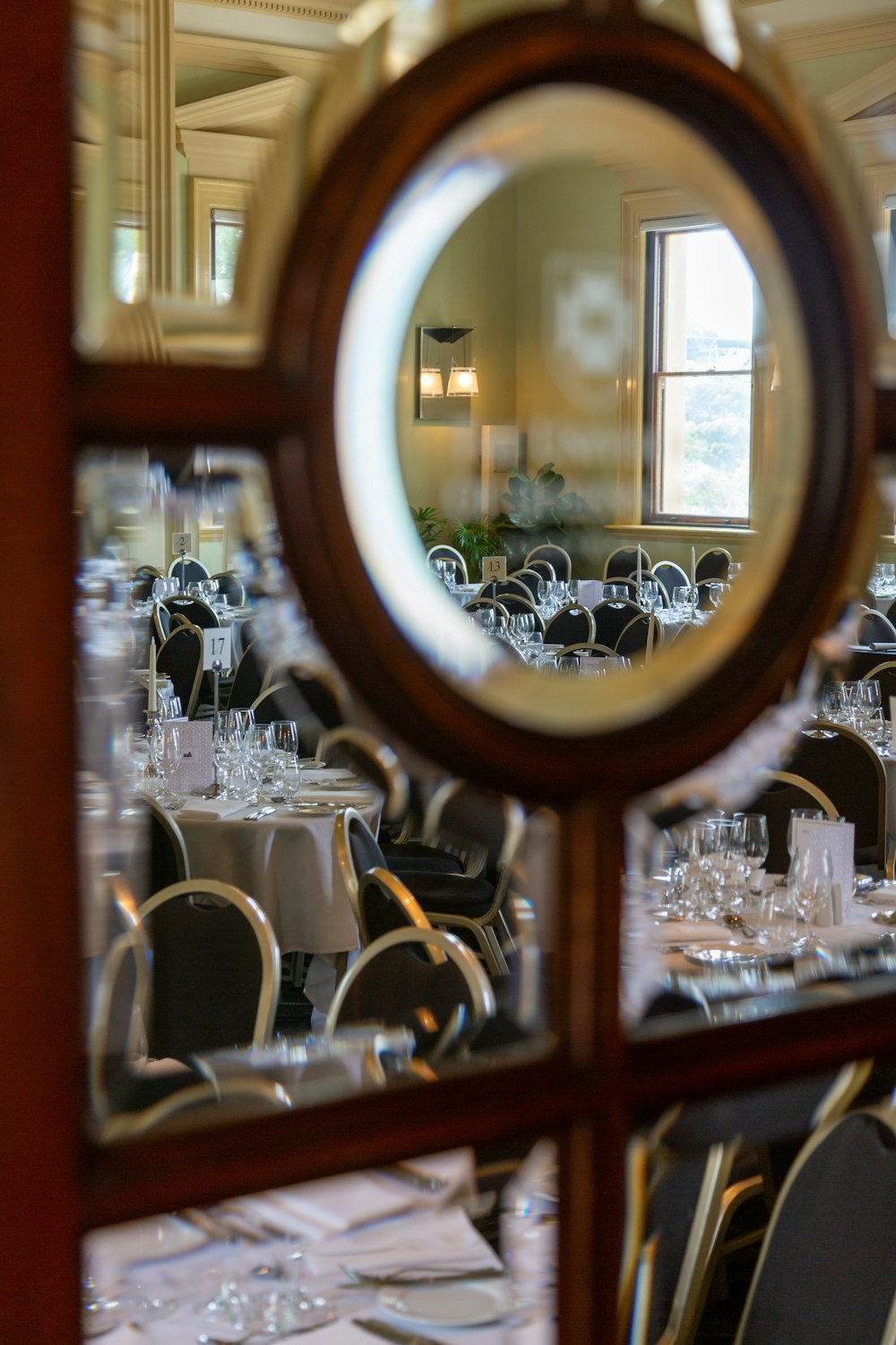 a mirror reflecting a dining room filled with tables and chairs