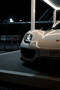 A sleek modern car showcased under bright city lights, highlighting its polished curves.