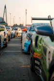 A group of drift cars lined up, ready for a race under bright lights.