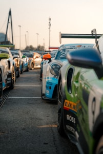 A group of legends cars lined up on a racetrack under a bright Finnish sky, ready for a race.